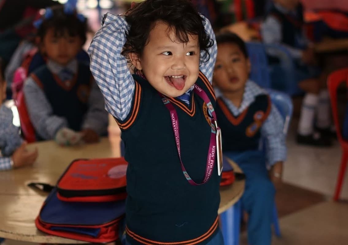 Happy early years child in Kids' Foundation school uniform smiling in classroom